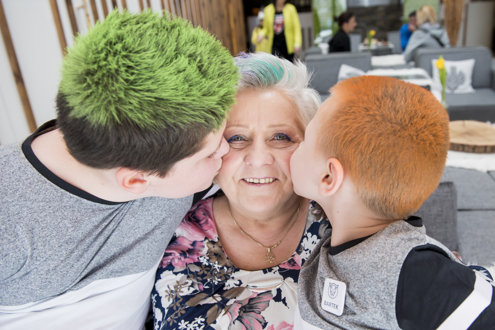 Dwoje dzieci całuje uśmiechniętą kobietę w policzki